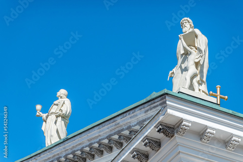 Helsinki, Finland - July 19, 2022: Matthew the Evangelist carrying writing instruments on SE corner of pediment with John the Apostle to his left against blue sky