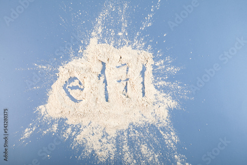 Titanium dioxide powder scattered on blue surface. TiO2 also known as titanium (IV) oxide or titania. Food additive, E171. Inorganic compound, white chemical alimentary pigment