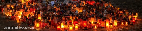 Setki zniczy świecących nocą na cmentarzu