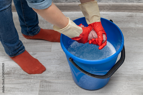 woman wringing out a wet rag in a bucket