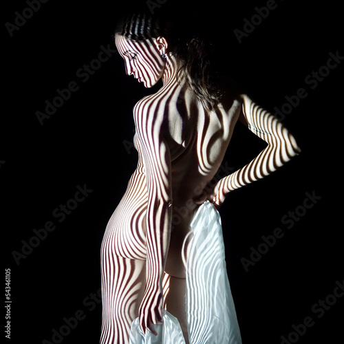 Projection with stripes from beamer or slide projector on young woman looks like body painting