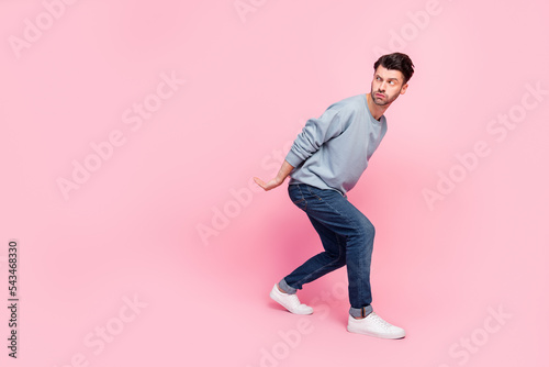 Full body photo of nice young man hold heavy box look suspicious empty space wear stylish blue clothes isolated on pink color background