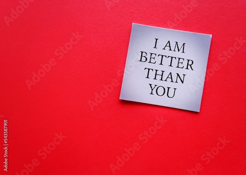 Card on red background with handwritten I AM BETTER THAN YOU - means SUPERIORITY COMPLEX, people who have belief that your abilities or accomplishments are dramatically better than someone else