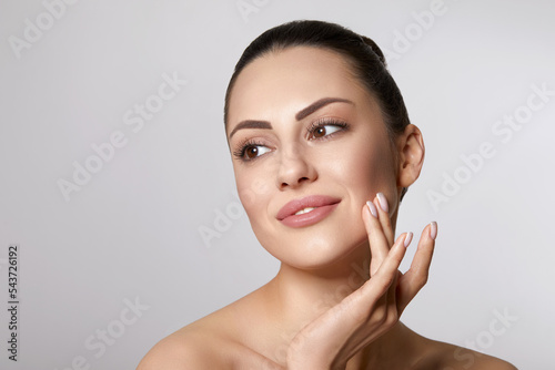Skin care. Woman with beauty face touching healthy facial skin portrait. Beautiful smiling girl model with natural makeup touching her skin
