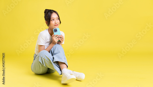 portrait of a beautiful young asian girl sitting on a yellow background