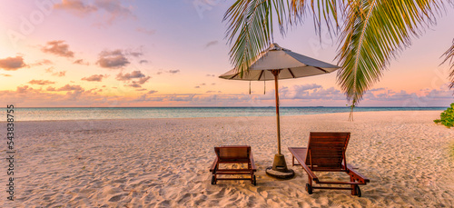 Beautiful panoramic nature. Tropical beach sunset as summer island landscape with chairs umbrella palm leaves calm sea shore, coast. Luxury travel panoramic destination banner for vacation or holiday 