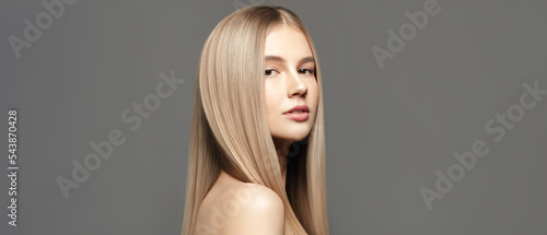Hair care. Beautiful young woman with long healthy hair posing against grey background. Beauty salon concept