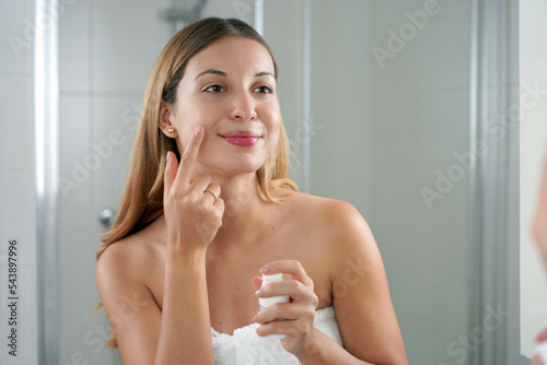 Skin care woman applying cream with retinol anti-signs in the bathroom