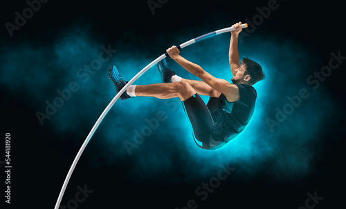 Professional pole vaulter training on black background