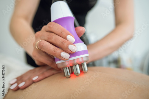 Beautiful woman receives procedure removing cellulite on her back with vacuum massage device