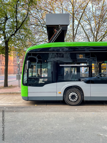 a modern electric bus is parked at the charging station and charges using a pantograph