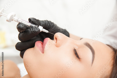 A cosmetologist gives a nose injection to fix the hump of a beautiful woman in a beauty salon. beauty injection.