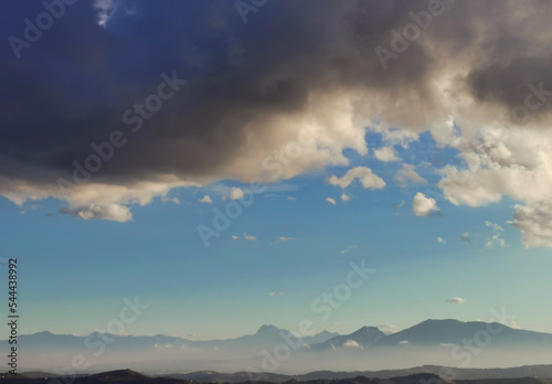 Nuvole bianche e nuvole nere nel cielo azzurro sopra i monti Appennini