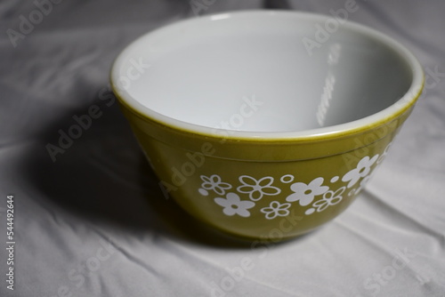 Green Pyrex bowl on white table cloth.