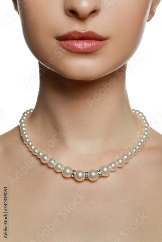 Young woman wearing elegant pearl necklace on white background, closeup