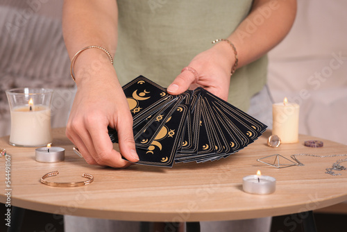 Soothsayer predicting future with tarot cards at table indoors, closeup