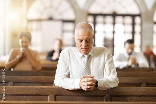 Praying, faith and in church to worship, spiritual and religion with believers, congregation and silent. Religious, connect and hands together for gratitude, closed eyes and prayer in tabernacle.