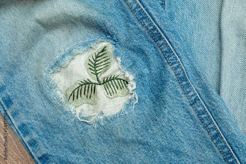 Old worn jeans with a patch sewn in place of a hole.Mending clothes concept.Reusing old jeans.Sustainable fashion,