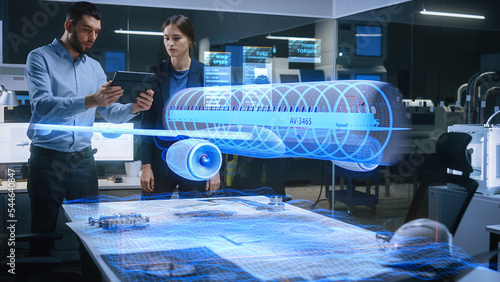 Aeronautics Factory Office Meeting Room: Engineer Holds Tablet Computer, Showing Augmented Reality Airplane Jet Engine to a Female Manager. Modern Industry 4.0 Project Research and Development Test.