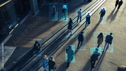 Elevated Security Camera Surveillance Footage of a Crowd of People Walking on Busy Urban City Streets. CCTV AI Facial Recognition Big Data Analysis Interface Scanning, Showing Personal Information.