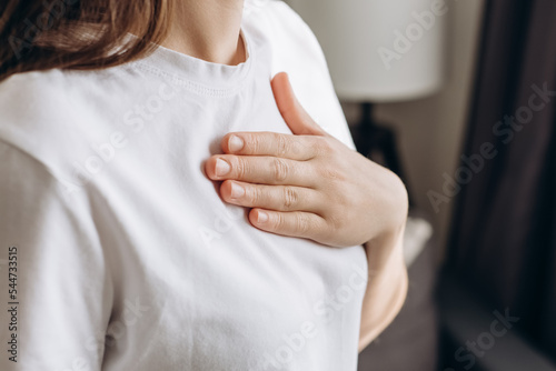 Close-up of ill young caucasian female putting hand on chest, feels discomfort. Having pain in chest, Gastroesophageal Reflux Disease have frequent belching. Healthcare medical and people concept