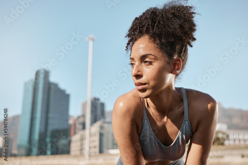 Fitness, runner and tired black woman in a city sweating from running exercise, cardio workout or training. Breathing, fatigue and sports athlete relaxing or resting on a break on a sunny summers day