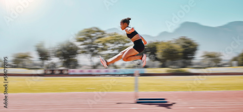 Athlete, sports and woman jump hurdle for track and field event for obstacle race or course for running, exercise and training for marathon. Female outdoor for sport, workout and energy at a stadium