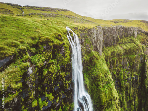 Aerial view of the top of the waterfall running over moss covered rocks in Iceland 