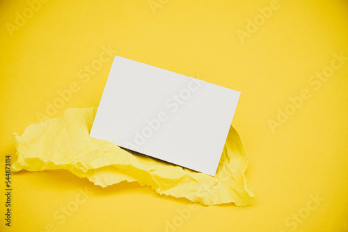 Blank business card over a yellow crepe paper against yellow background