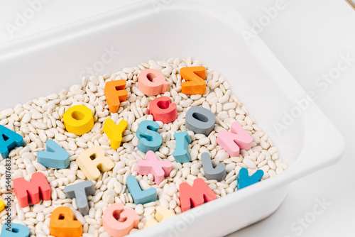 Colorful letters of the alphabet in sensory bin. Primary school or preschool, kindergarten. Educational game. Learning through play. Sensory play for toddlers..