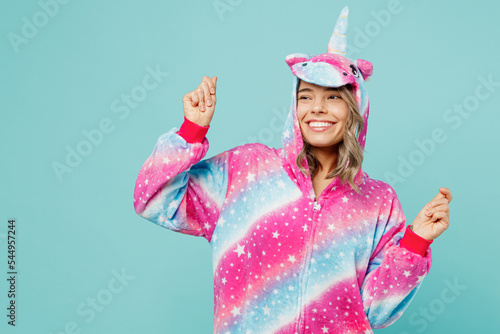 Young fun woman wear domestic costume with hoody and animals ears raise up hands look aside on area dance on pajama party isolated on plain pastel light blue cyan background People lifestyle concept