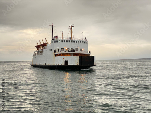 Traversier sur l'eau par une journée nuageuse et grise. Ferry arrivant à bon port. Bateau de croisière sur le fleuve près d'une marina Transport des automobiles d'une rive à l'autre.