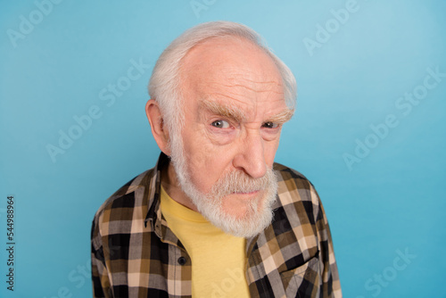 Photo of suspicious unsure retired man wear plaid shirt looking you isolated blue color background