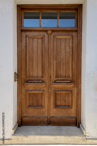 Stylish wooden front door with glass window above in white stone doorway 