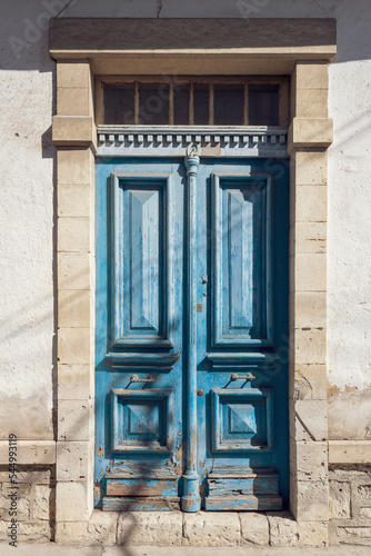 Blue old-fashioned shabby wooden front door in natural stone doorway 