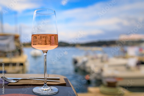 Glass of rose wine on a table with Mediterranean Sea and boats in background in Villefranche sur Mer Old Town on the French Riviera, South of France
