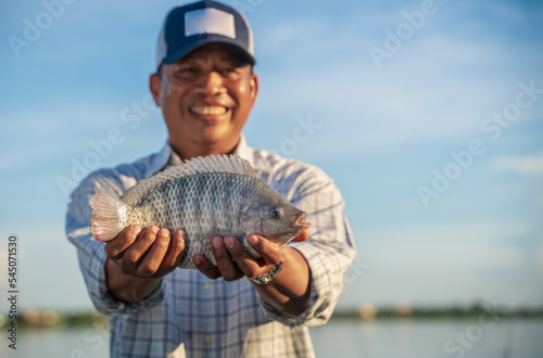 Aquaculture farmer man showcasing quality-raised tilapia in his hands
