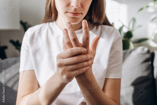 Cropped shot unhealthy female massage hand with wrist pain, rheumatoid arthritis. Young woman suffer from numbing pain in hand, numbness fingertip, arthritis inflammation, peripheral neuropathies