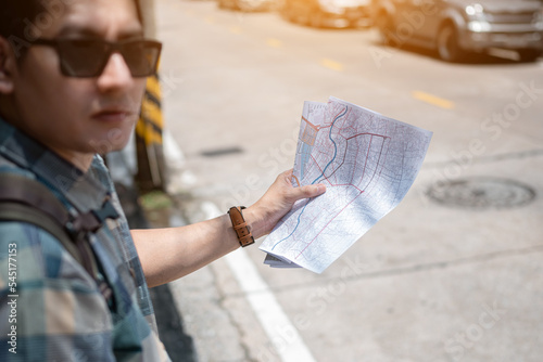 Traveler standing on the street and looking direction on location map.