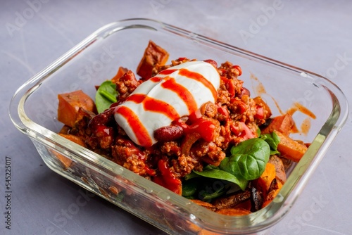 Tasty dish of minced meat, fresh spinach, squash served with red and white sauces in a pyrex