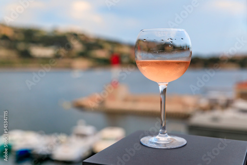 Glass of rose wine on a table with Mediterranean Sea and boats in background in Villefranche sur Mer Old Town on the French Riviera, South of France