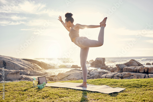 Yoga, training and woman with tablet at the beach with instructions from online fitness video. Wellness, nature and black woman in stretching exercise on yoga mat with workout tutorial by ocean