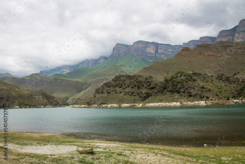 Turquoise water Lake Gizhgit among the hilly picturesque shores in the Elbrus region in Kabardino-Balkaria on a cloudy dramatic day and a space to copy