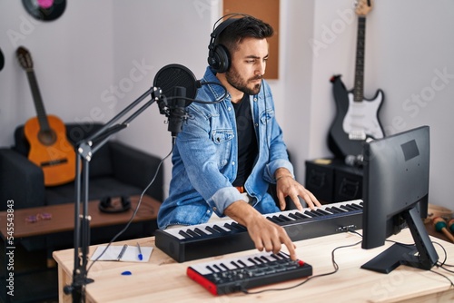 Young hispanic man composer composing song at music studio