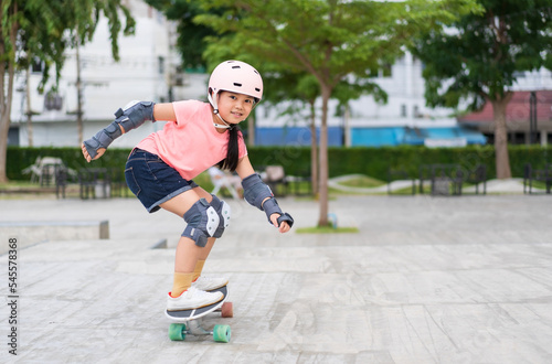 asian child skater or kid girl smile playing skateboard or fun riding surf skate carving in skate park for extreme sports exercise to wearing helmet elbow wrist knee support for body safety protect