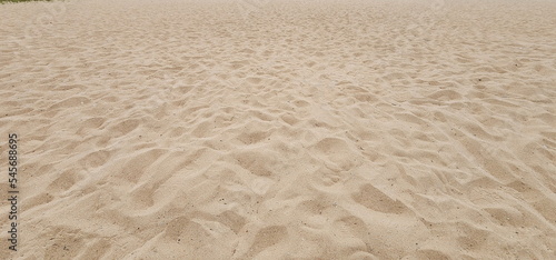 Sand with footprints of tourists. Beach on an uneven summer morning due to footprints. Textured surface of a sandy beach 