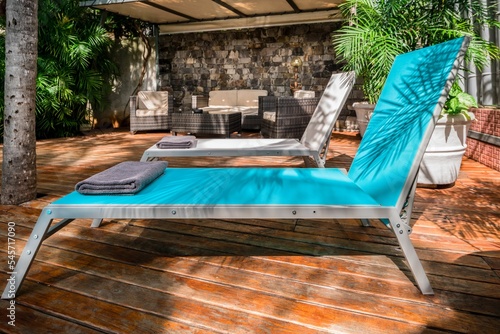 lounger chairs on a pool deck surrounding by tropical vegetation and furniture in the background