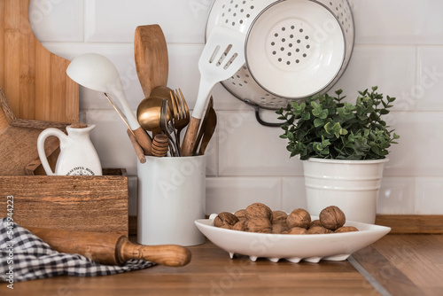 Dishes and cutlery on the kitchen wooden countertop, ready to cook. White modern kitchen in Scandinavian style, kitchen details.