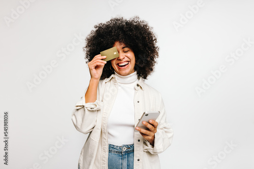 Happy young woman holding a credit card and a smartphone