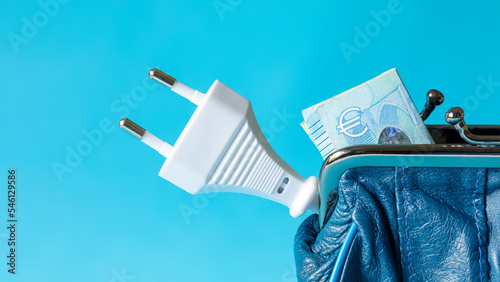 Euro banknote and an electricity plug in a blue leather wallet on blue background. The concept of increasing the cost of electricity, payment for electricity. Energy crisis concept